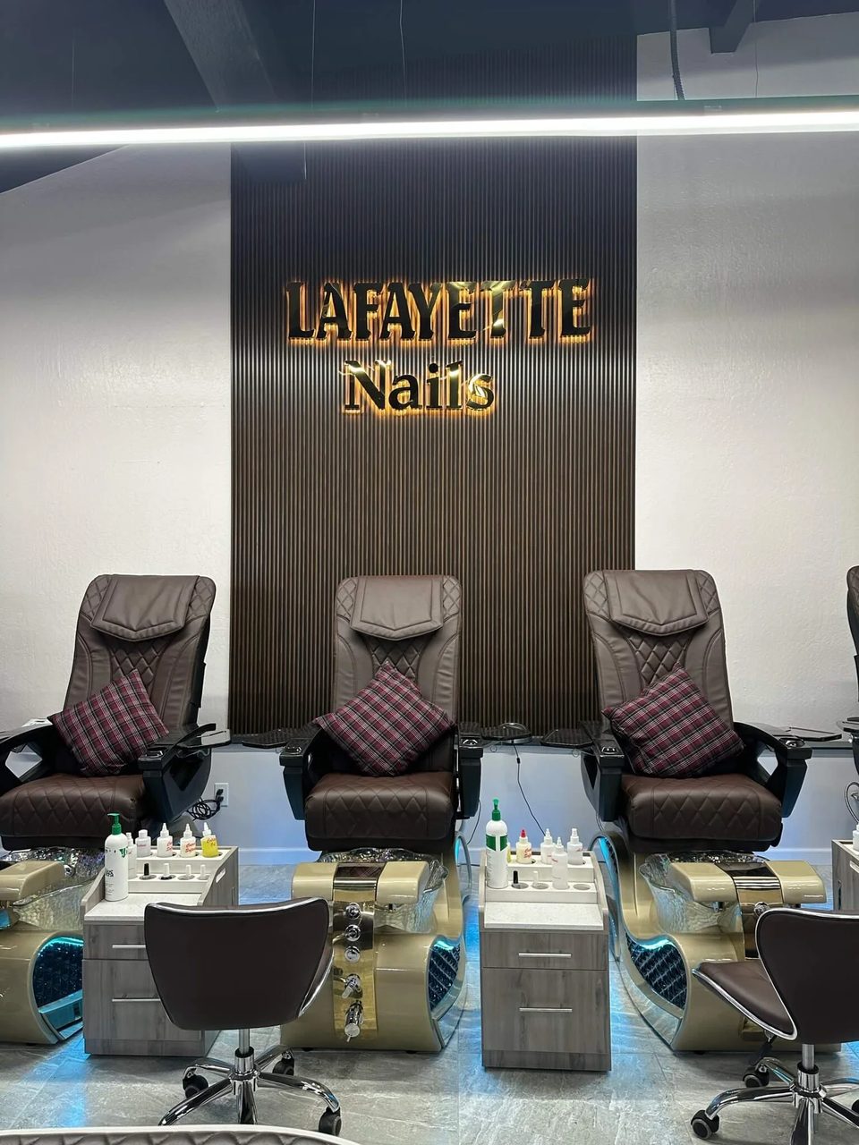 Inside Lafayette Nails: espresso leather pedicure chairs beneath the gold Lafayette Nails sign on a slatted wood wall