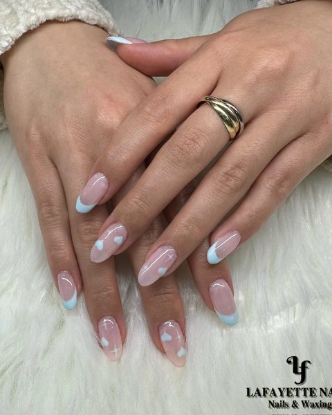 Soft nude almond nails with pale blue French tips and tiny hearts