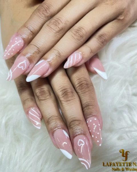 Long pink almond nails with white swirls, hearts and dots