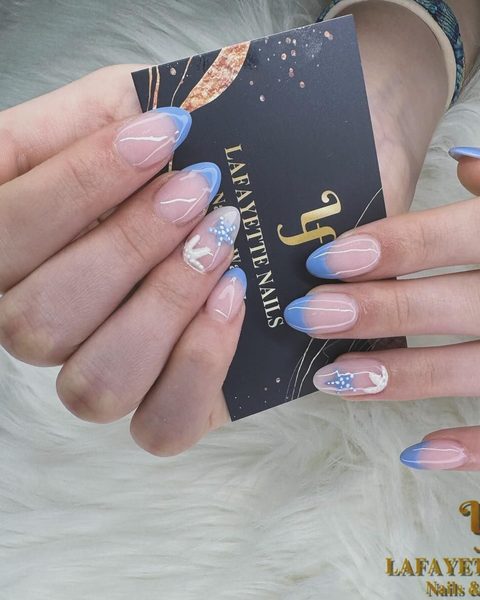 Blue ombre French almond nails with a snowflake accent, holding a Lafayette Nails business card