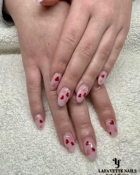 Sheer pink nails scattered with little red hearts